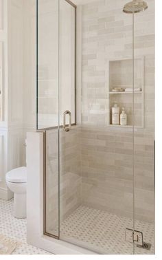 a bathroom with a walk in shower next to a white toilet and tiled flooring