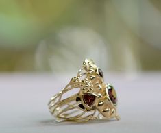 Elegant gold intertwines and blooms with garnet flowers in this Art Nouveau-inspired elaborate ornament ring. 14k gold, garnet Size 7 1/2 available now, other sizes can be made to order Gold Multi-stone Garnet Jewelry, Gold Garnet Multi-stone Jewelry, Unique Gold Garnet Jewelry, Unique Garnet Gold Jewelry, Gold Garnet Multi-stone Ring, Art Nouveau Ornament, Pebble Ring, Smoky Quartz Ring, Flower Engagement Ring