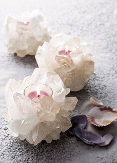 three glass flowers sitting on top of a sandy beach