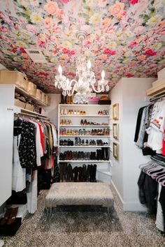 a walk in closet with chandelier hanging from the ceiling and shoes on shelves