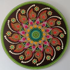 a circular painting on the wall with an intricate design in green, orange and pink