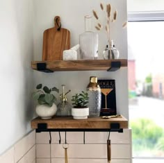 two wooden shelves with plants and vases on them in the corner of a bathroom