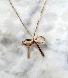 "Dress up your outfit with this dainty bow ribbon pendant necklace!  JEWELRY DETAILS: ◦ Necklace chain: 16K gold plated over brass ◦ Pendant: 18K gold plated over brass, Herringbone chain ◦ Pendant measures 36~39mm length, 37~39mm wide ◦ Necklace length options: 15\", 16\", 17\", 18\" ◦ Nickle-free and lead-free jewelry JEWELRY CARE TIPS: ◦ Store jewelry in a cool and dry place, keep away from moisture ◦ Remove before exercising, sleeping, and entering water ◦ Avoid contact with perfumes, lotion Gold Necklace With Ribbon For Gift, Gold Necklace With Ribbon Perfect For Gifts, Adjustable Necklace With Decorative Bow As Gift, Adjustable Necklace With Decorative Bow For Gifts, Dainty Gold Jewelry With Ribbon, Formal Gold Necklaces With Ribbon, Formal Gold Necklace With Ribbon, Formal Gold Ribbon Necklace, Gold Bow Necklaces For Gifts