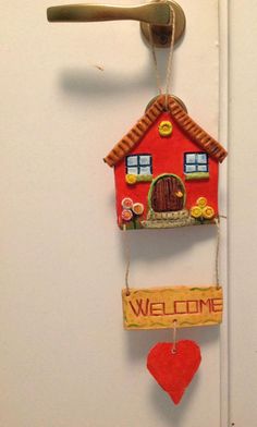 a red house hanging from the side of a door with a welcome sign attached to it