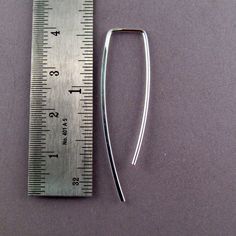 a measuring ruler with a metal clip next to it on a purple surface, showing the length