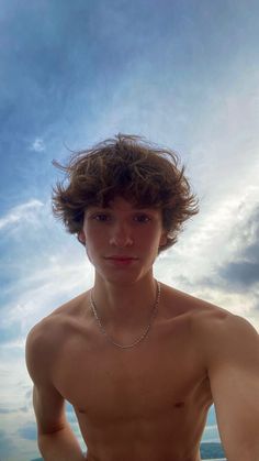 a shirtless young man standing on the beach