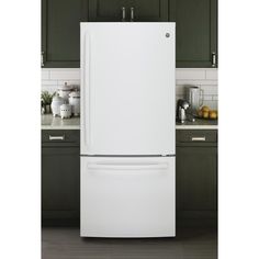 a white refrigerator freezer sitting inside of a kitchen next to green cabinets and counter tops