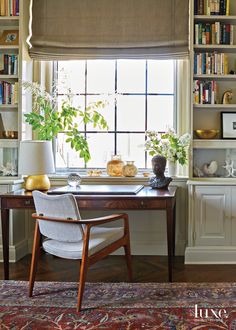 a home office with bookshelves, desk and chair in front of the window