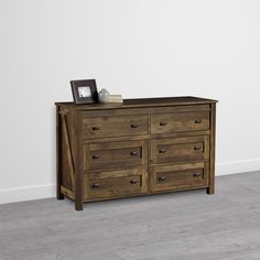 a wooden dresser sitting on top of a hard wood floor next to a white wall