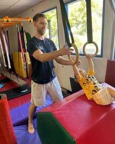 a man is playing with a small child on a trampoline in a gym