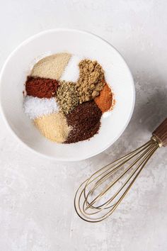 a bowl filled with spices next to a whisk