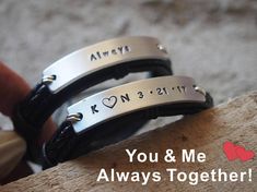 two black leather bracelets with engraved names and hearts on the side, one saying you & me always together