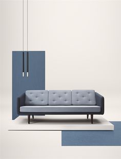 a blue couch sitting on top of a white rug next to a tall light fixture