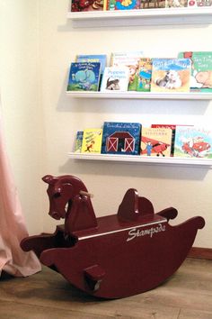 a wooden rocking horse with books on the shelves