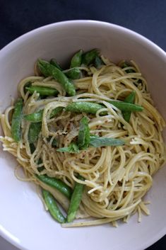 a white bowl filled with pasta and green beans