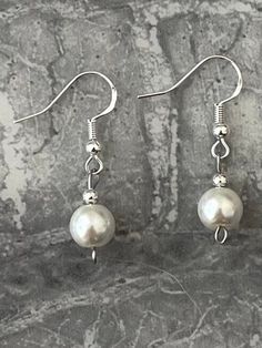 Silver pearl drop earrings.  Add a touch of elegance to your wardrobe with these timeless earrings. Handmade with love to elevate any look. Sterling silver ear hook with a simple but classy faux pearl drop. hypoallergic. Free shipping to UK buyers. Dispatched within 1-3 days via Royal Mail.  Presented on a gift card and wrapped beautifully in luxury tissue paper and a blush pink organza bag making them the perfect little gifts.  If you aren't completely in LOVE with your purchase, please let me know and you'll receive a stress free refund. Customer satisfaction is my key priority.  These are perfect for any occasion or outfit.  Thank you for viewing. Please ask any questions, I am always available to help.  I have lots of styles available so if you have a spare few minutes please have a lo Classic Earrings For Bridesmaid Gift, Classic Silver Bridal Earrings With Pearl Drop, Elegant White Jewelry With French Hook, Minimalist White Bridal Earrings With Ear Wire, Silver Pearl Earrings With French Hook For Formal Events, Silver Pearl Earrings With French Hook For Formal Occasions, Silver Graceful Pearl Drop Earrings, Feminine Silver Pearl Drop Earrings, Simple Silver Pearl Drop Jewelry