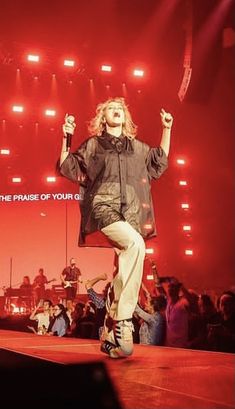 a woman standing on top of a stage with her arms in the air