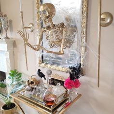 a table with a skeleton on it in front of a mirror and candlesticks