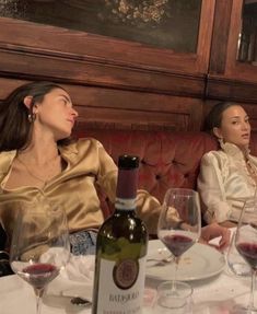 two women sitting at a table with wine glasses