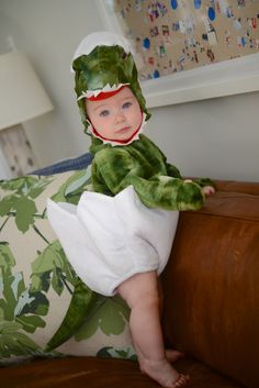 a baby in a frog costume sitting on a couch