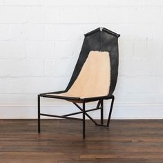 a black and white chair sitting on top of a hard wood floor next to a brick wall