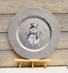 a snowman plate sitting on top of a wooden table next to a white board