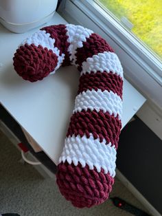 a red and white knitted object sitting on top of a table next to a window