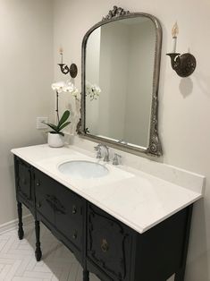 a bathroom vanity with a large mirror above it and a vase on the counter top