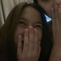 two young women covering their faces with hands