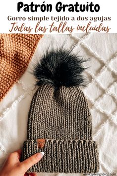 a knitted hat with a black pom - pom on top and text overlay