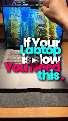 a laptop computer sitting on top of a wooden desk next to a person's hand