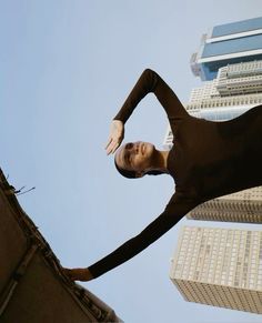 a woman standing on top of a roof next to tall buildings