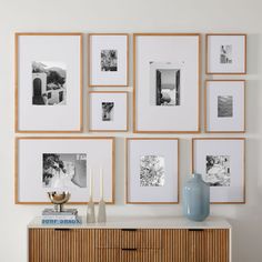 a wall with many frames and vases on it next to a dresser in a room