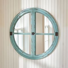 a round mirror mounted to the side of a wall next to a white and blue striped wall