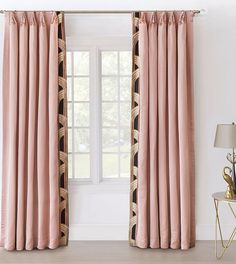 the pink curtains are hanging in front of a window with an ornate pattern on it