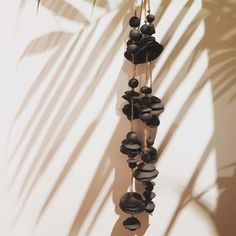 a wind chime hanging from the side of a wall with rocks and leaves on it