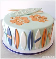 a surfboard cake is decorated with blue and orange icing