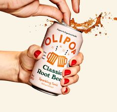 two hands holding a can of beer with orange and brown sprinkles on it