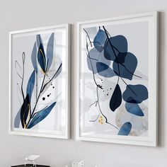 two blue and white paintings hanging on the wall above a desk in front of a window