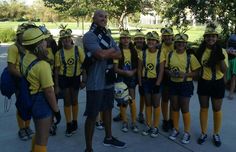 a man standing in front of a group of girls wearing yellow shirts and backpacks