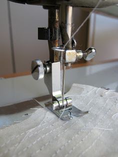 the sewing machine is working on something white or gray fabric that has been stitched together