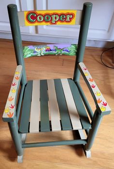 a green and white wooden rocking chair with the word cooper painted on it's side