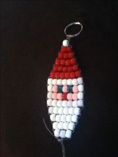 a beaded santa clause ornament hanging on a black background with red, white and blue beads