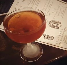 a close up of a drink in a wine glass on a table with menus