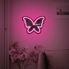 a pink neon sign with a butterfly on it's side in front of a wall