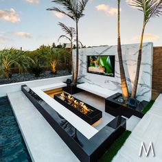 an outdoor living area with palm trees and a flat screen tv mounted on the wall