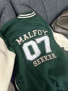 a green jersey with white lettering on the chest and sleeves that says malfoy