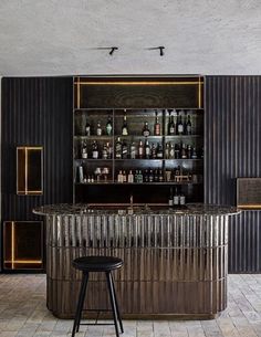 a bar with stools in front of it and bottles on the shelves behind it