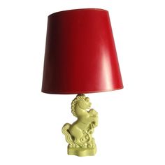 a lamp with a red shade on the base and a yellow lion figurine underneath it