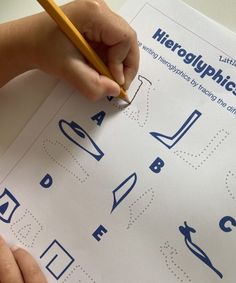 a child's hand is writing on a sheet of paper with blue letters and numbers